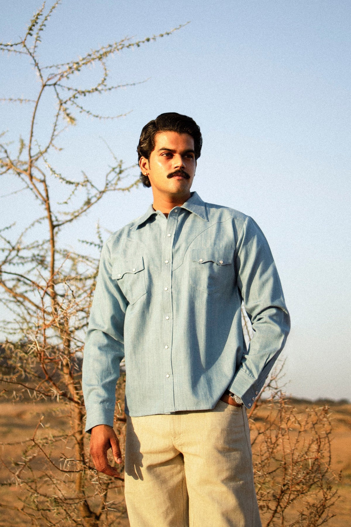 Man standing in a desert landscape with a clear blue sky