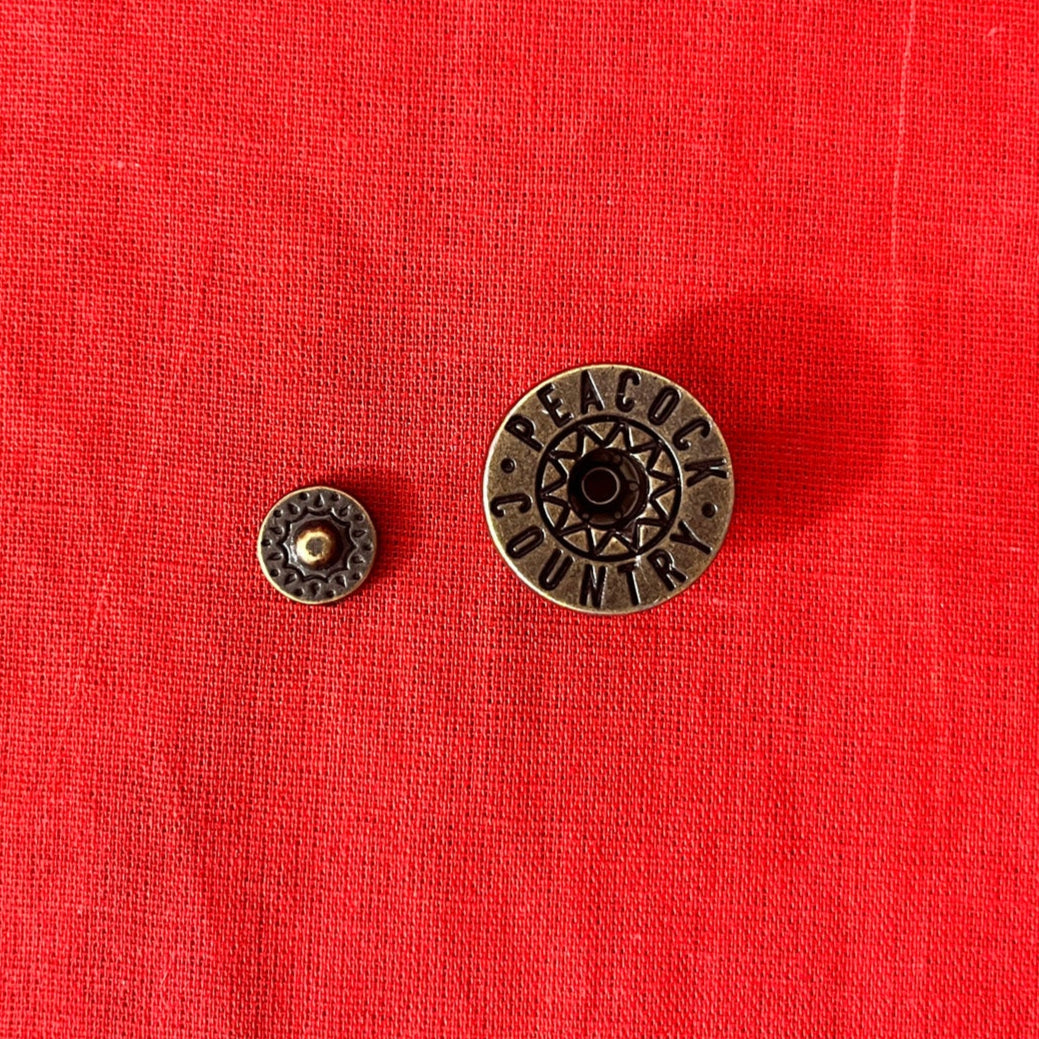 Two metal buttons on a red fabric background